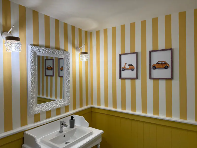 Décoration du restaurant Gusto : murs rayés jaune et blanc, miroir et lave-mains